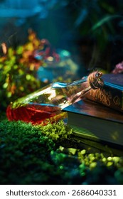 potion bottle filled with red liquid tilts beside a worn, ancient book on a bed of green moss. Soft light glimmers through surrounding plants, creating a magical atmosphere.