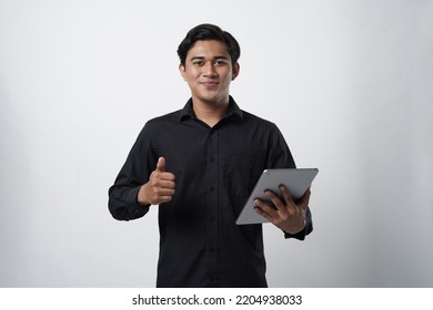 Potrait Of Asian Guy Millenial. Work Online, Freelance, Teacher And Blogger. Smiling Cute Young Male In Casual Black Looks In Digital Tablet And Surfing On Internet, Isolated On White Background, Stud