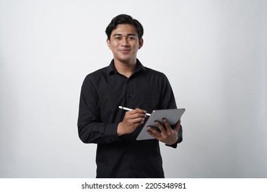 Potrait Of Asian Guy Millenial. Work Online, Freelance, Teacher And Blogger. Smiling Cute Young Male In Casual Black Looks In Digital Tablet And Surfing On Internet, Isolated On White Background, Stud