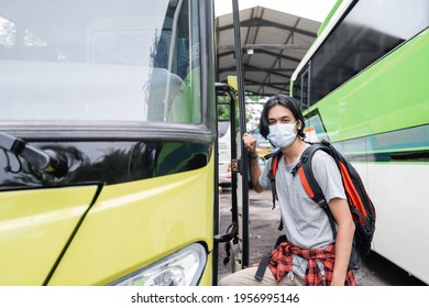 Potrait Asian Young Man Wearing Face Masks Getting On The Bus.A Man Wearing A Face Mask And Carrying A Backpack Gets On The Bus At The Terminal