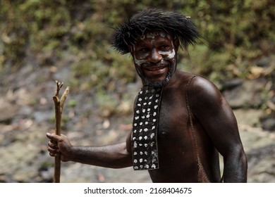 Potrait of Dani tribe man from Wamena Papua Indonesia wearing traditional clothes for hunting is smiling against blurred greenery forest background. - Shutterstock ID 2168404675