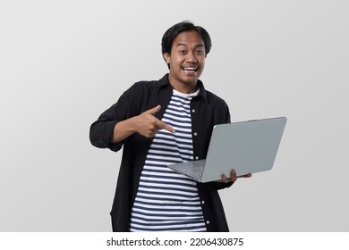 Potrait Of Male Asian Student, Smiling Young Man In Jeans Shirt Pointing Finger On Computer Over White Background.