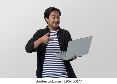 Potrait Of Male Asian Student, Smiling Young Man In Jeans Shirt Pointing Finger On Computer Over White Background.