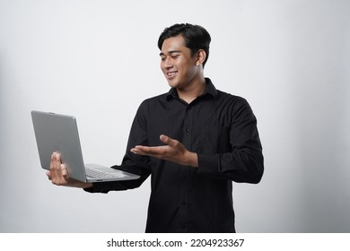 Potrait Of Smiling Asian Young Asian Man In Black Casual Shirt Pointing Finger On Computer Over White Background.