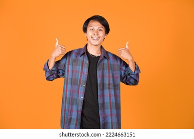 Potrait Of Smiling Asian Young Man Wearing Shirt Showing Good Gesture With Thhumbs Up Isolated On Yellow Background