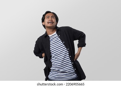 Potrait Of Young Asian Man, Suffering From Backache For Having Made An Effort Over Isolated White Background