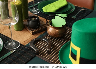Pots with paper clover, coins, horseshoe and leprechaun's hat on table served for St. Patrick's Day celebration, closeup