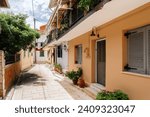 Potted flowers line the sun-washed walls of a charming alleyway in a picturesque Mediterranean village, inviting a leisurely stroll