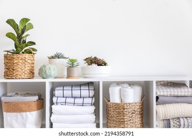 Potted plants in ecology straw baskets on shelf of bed linens cupboard textile arrangement storage organization. Minimalism Scandi placed method neatly folded cotton fabric bedding material copy space - Shutterstock ID 2194358791