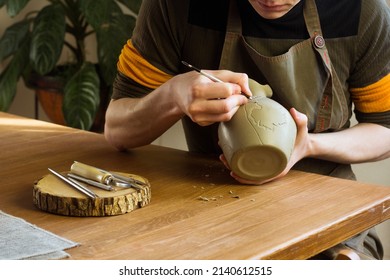 Potter carving ornament on jug. Master working in Pottery studio with equipment Wooden Modeling Tools set. Ribs, Loop, Wire, Ribbon tool - Powered by Shutterstock