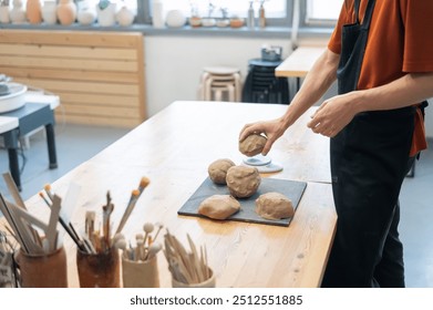 A potter kneads clay before using it in the workshop. Close-up of a man's hands.  - Powered by Shutterstock