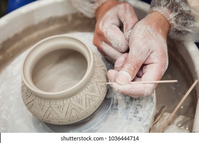 potter make a decorative pattern on pot