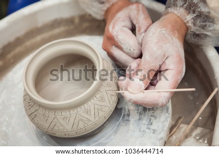 potter make a decorative pattern on pot