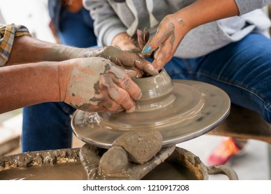 Potter makes on the pottery wheel clay pot. The hands of a potter with the tool, close-up.