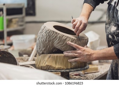 Potter at work. Close-up of man hands making ceramic sculpture on his workshop
