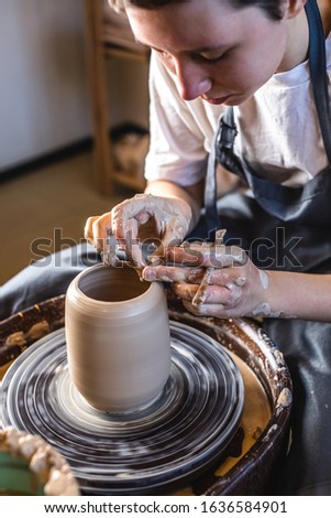 Similar – Young female sitting by table and making clay or ceramic mug