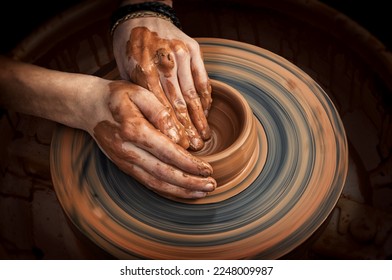 Potter's hands while working on the wheel, top view with dark background. Master makes a pot on a potter's wheel - Powered by Shutterstock