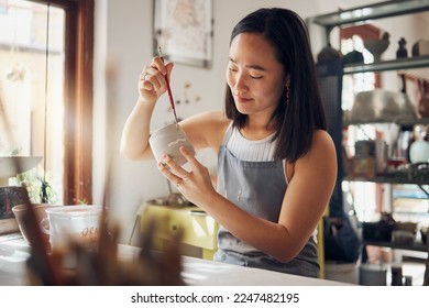 Pottery, art and design with an asian woman in a studio for her creative ceramics hobby as an artisan. Manufacturing, pattern and artist with a female potter sitting in her workshop as a sculptor - Powered by Shutterstock