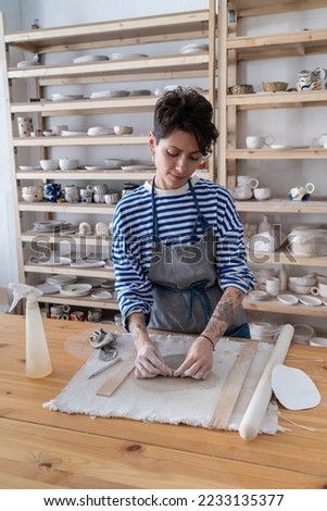 Similar – Young female sitting by table and making clay or ceramic mug