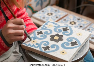 A Pottery Decorator Painting A Ceramic Tile With Floral Motifs In His Work Table In Caltagirone, Sicily