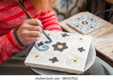 A Pottery Decorator Painting A Ceramic Tile With Floral Motifs In His Work Table In Caltagirone, Sicily