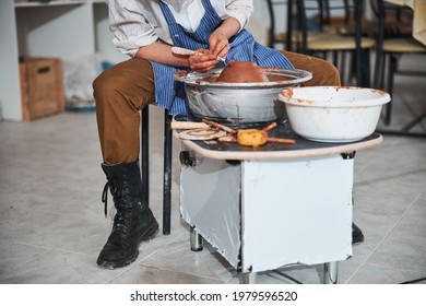 Pottery designer taking off clay from dish on electric wheel