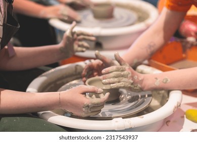 Pottery lesson master class for kids children, process of making clay pot on pottery wheel, potter wet hands creating ceramic crockery handcrafts, ceramist molding jar or vase - Powered by Shutterstock