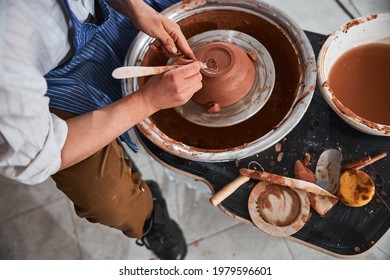 Pottery master forming the back of clay bowl with instrument