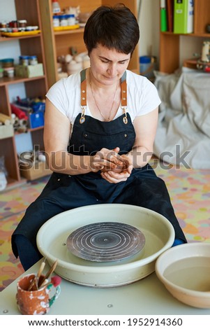 Similar – Young female sitting by table and making clay or ceramic mug