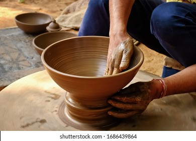Pottery - skilled wet hands of potter shaping the clay on potter wheel. Pot, vase throwing. Manufacturing traditional handicraft Indian bowl, jar, pot, jug. Shilpagram, Udaipur, Rajasthan, India