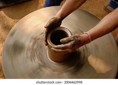 Pottery - skilled wet hands of potter shaping the clay on potter wheel. Pot, vase throwing. Manufacturing traditional handicraft Indian bowl, jar, pot, jug. Shilpagram, Udaipur, Rajasthan, India - Powered by Shutterstock