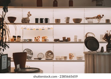 Pottery tablewares on shelves of small art shop. Handmade ceramic pottery objects in art studio workspace. Ceramic Shop's Products.