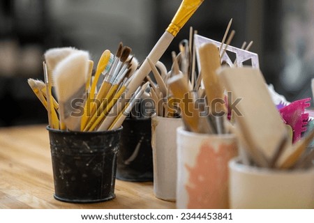 Pottery tools on wooden table in creative studio.