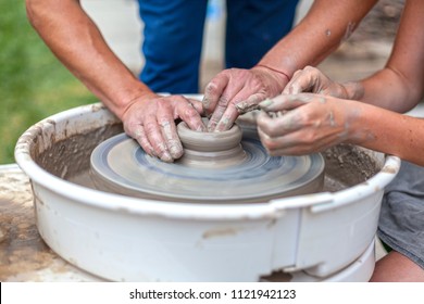 pottery training, a close-up of a man potter teaches a woman how to properly mold a bowl of brown clay on a potter - Powered by Shutterstock