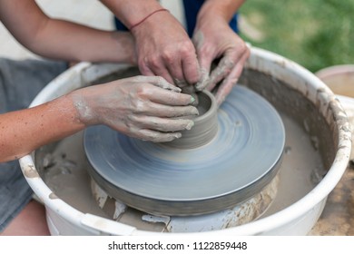 pottery training, a close-up of a man potter teaches a woman how to properly mold a bowl of brown clay on a potter - Powered by Shutterstock