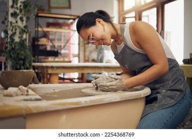 Pottery wheel, workshop and startup business woman manufacturing creative art product with hands. Happy asian potter artist working in clay or ceramics retail industry, studio or class with pride - Powered by Shutterstock