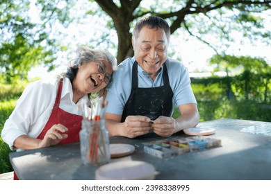 In the pottery workshop, an Asian retired couple is engaged in pottery making and clay painting activities. - Powered by Shutterstock