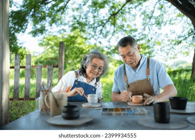 In the pottery workshop, an Asian retired couple is engaged in pottery making and clay painting activities. - Powered by Shutterstock