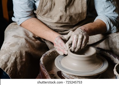 pottery, workshop, ceramics art concept - closeup on male hands sculpt new utensil with a tools and water, man's fingers work with potter wheel and raw fireclay, front close view - Shutterstock ID 725245753