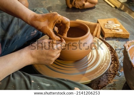 pottery, workshop, ceramics art concept - closeup on male hands sculpt new utensil with a tools and water, man's fingers work with potter wheel and raw fireclay, front close view.