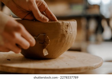 In the pottery workshop the master processes the product with loop for clay sculpts clay dishes on table - Powered by Shutterstock