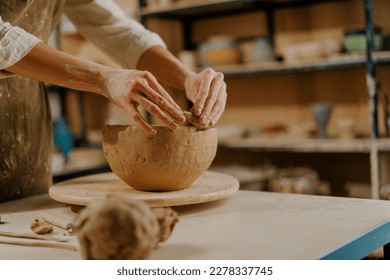 In the pottery workshop the master sculpts clay dishes with his hands on table - Powered by Shutterstock