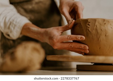 In the pottery workshop the master sculpts clay dishes with his hands on table - Powered by Shutterstock