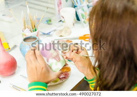 Pottery.Drawing and painting flower (orchid) on ceramic cup.