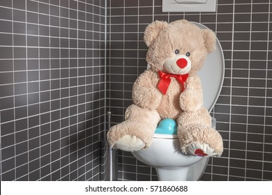 Potty training concept, toy teddy bear sitting on toilet bowl in bathroom, early childhood, children toilet training, motherhood and hygiene concept