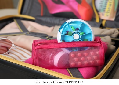 Pouch with different medicaments and pill box in packed suitcase, closeup - Shutterstock ID 2113131137