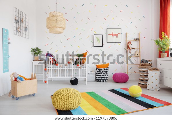 スカンジの赤ちゃんの寝室の内部にランプ 揺りかご ポスターを持つカラフルな絨毯の上にポフ 本物の写真 の写真素材 今すぐ編集