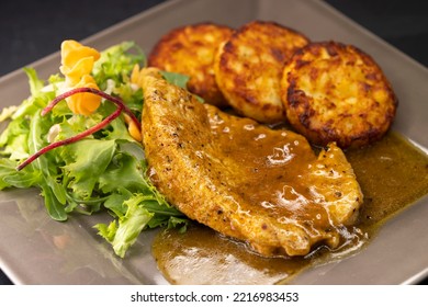 Poultry Meat With Sauce Served With Hash Browns And Salad