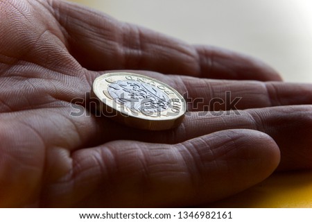 Pound coin in palm of hand close up