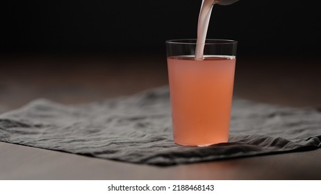 Pour Guava Drink From Can Into Tumbler Glass On Table, Wide Photo